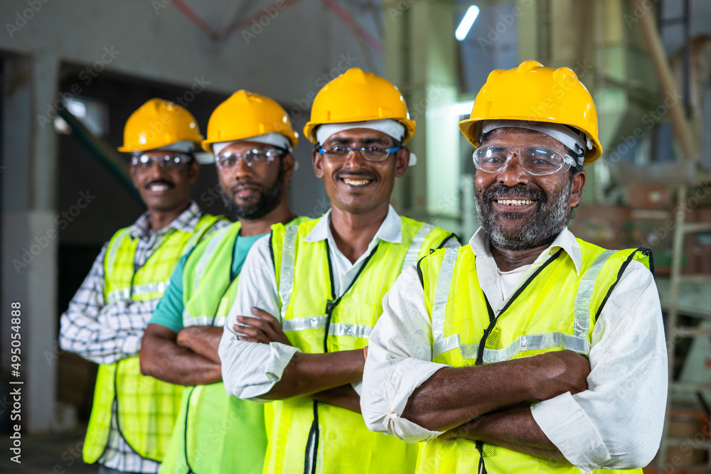 Confidently standing industrial workers with arms crossed by looking at camera - concept of workforce, occupation and safety