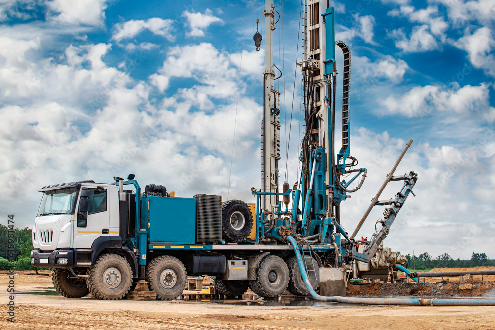 Work of a drilling rig at a construction site against a background of blue sky. Exploration of useful minerals. Industry and construction.